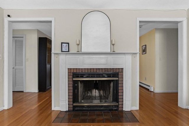 details featuring a baseboard heating unit, wood finished floors, a fireplace, and baseboards