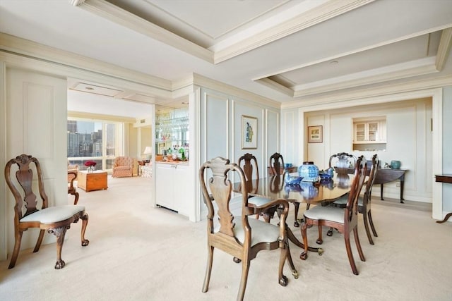 carpeted dining room featuring a raised ceiling and ornamental molding