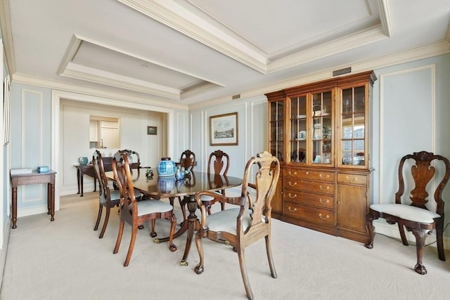 dining area with crown molding, light colored carpet, and a raised ceiling