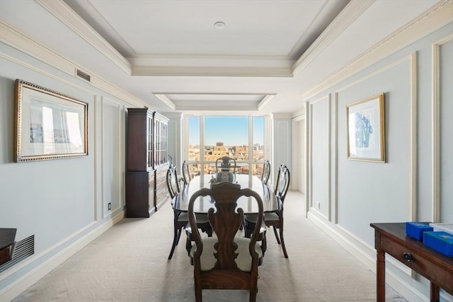 carpeted dining space with ornamental molding and a raised ceiling