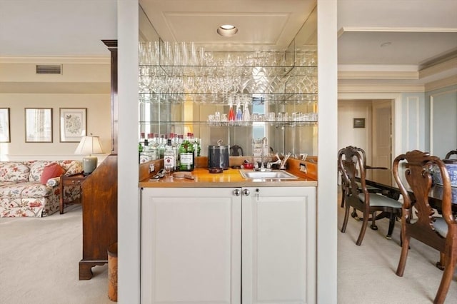 bar featuring light carpet, sink, and crown molding