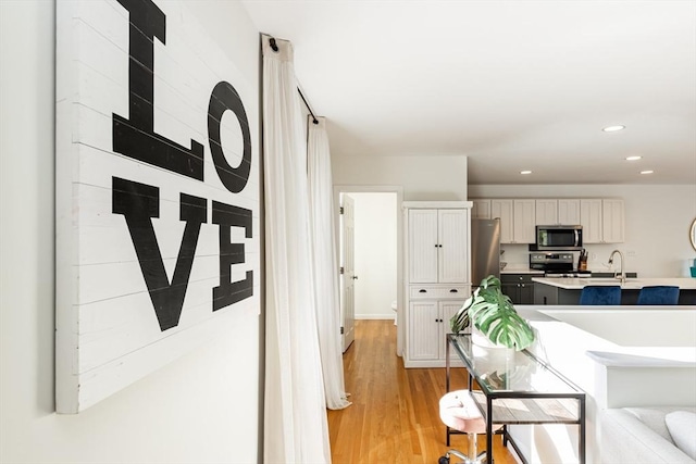 kitchen with white cabinetry, light hardwood / wood-style flooring, sink, and appliances with stainless steel finishes