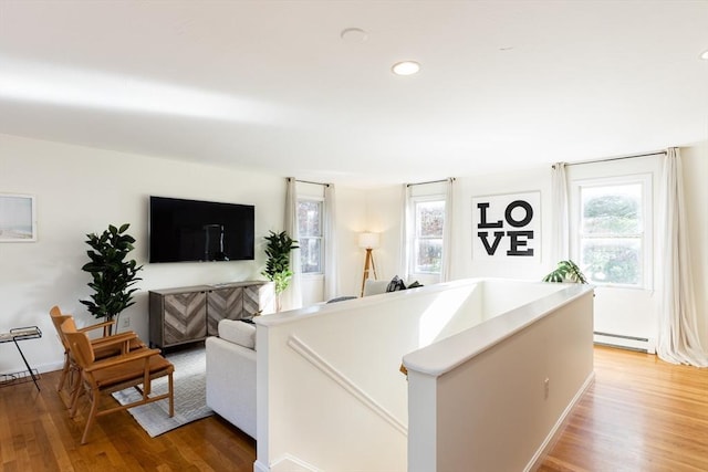 living room featuring wood-type flooring and a baseboard heating unit