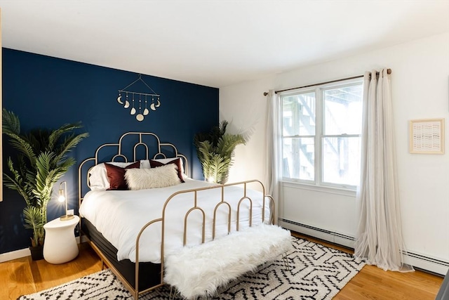 bedroom with hardwood / wood-style flooring and baseboard heating