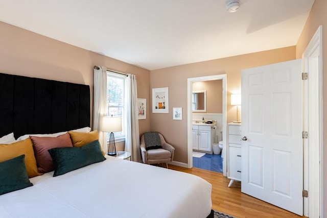 bedroom featuring connected bathroom and light hardwood / wood-style floors