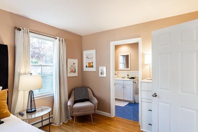 living area featuring light wood-type flooring, a baseboard radiator, and a healthy amount of sunlight