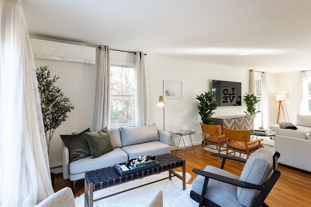 living room featuring wood-type flooring, a wall unit AC, and baseboard heating