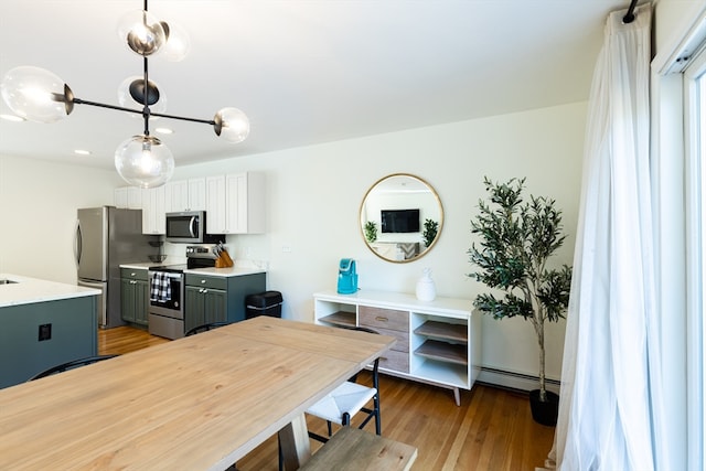 kitchen with stainless steel appliances, a baseboard radiator, pendant lighting, light hardwood / wood-style floors, and gray cabinets