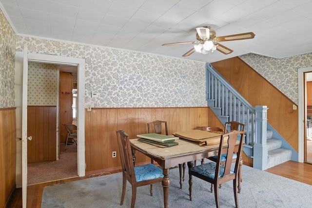 dining room with wood finished floors, ornamental molding, stairway, wainscoting, and wallpapered walls