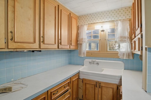 kitchen featuring backsplash, light countertops, and a sink