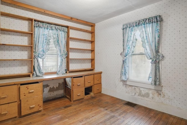 home office with light wood-type flooring, wallpapered walls, baseboards, and visible vents