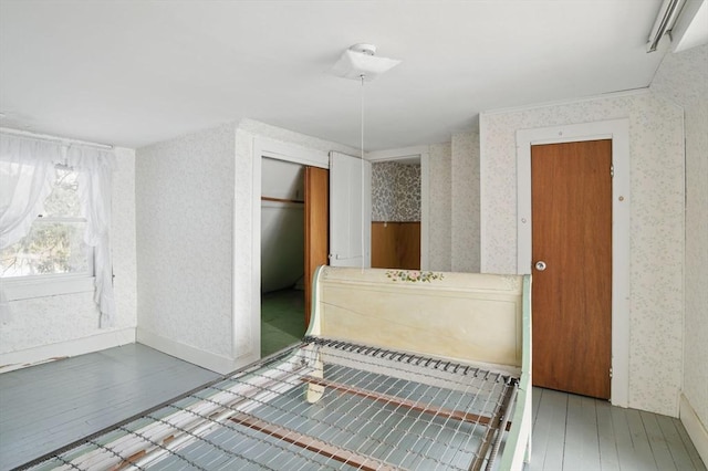 bathroom featuring baseboards, hardwood / wood-style floors, and wallpapered walls