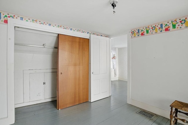 unfurnished bedroom featuring a closet, dark wood finished floors, visible vents, and baseboards