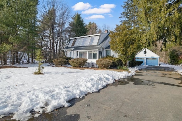 view of front of property featuring a garage, a chimney, and an outdoor structure