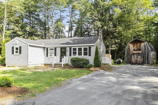 58 Mattawa Cir, Orange, MA 01364 - view of front of house featuring a storage unit, a chimney, a shingled roof, and a front yard