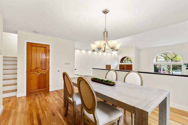 dining space with baseboards, an inviting chandelier, stairway, and light wood-type flooring