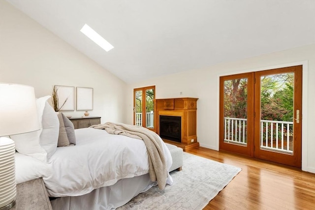 bedroom with vaulted ceiling with skylight, baseboards, access to outside, and light wood finished floors
