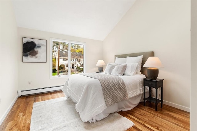 bedroom featuring baseboards, baseboard heating, lofted ceiling, and wood finished floors