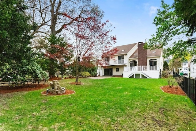 back of house featuring fence, a wooden deck, a lawn, and stairway