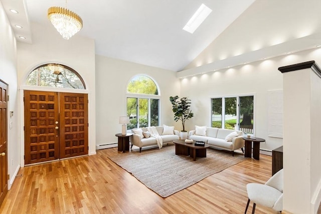 living room with an inviting chandelier, high vaulted ceiling, plenty of natural light, and baseboard heating