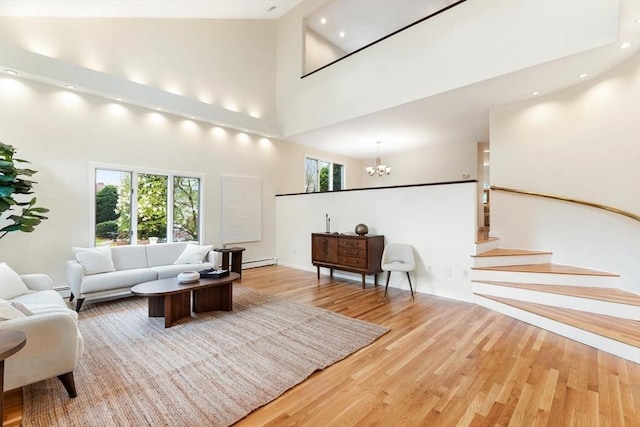 living area with wood finished floors, high vaulted ceiling, a healthy amount of sunlight, and a baseboard radiator