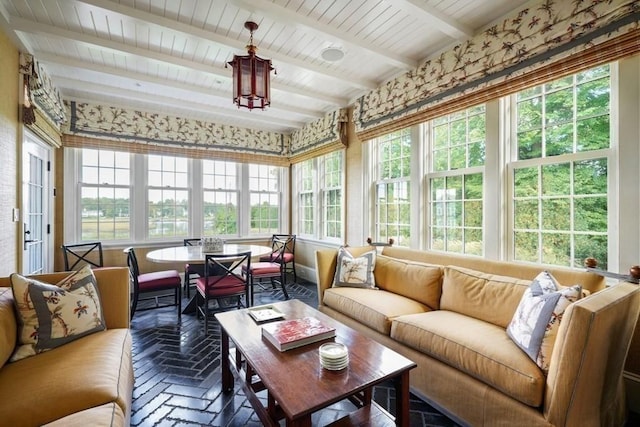 sunroom featuring brick floor, a healthy amount of sunlight, and beamed ceiling