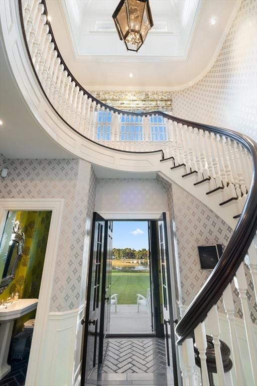entrance foyer with wallpapered walls, ornamental molding, stairs, and wainscoting