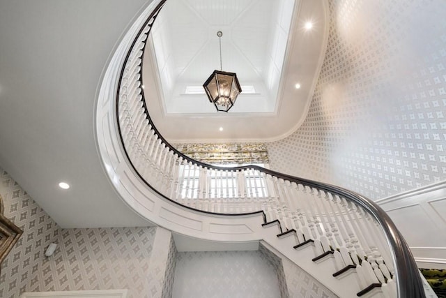 stairs with a high ceiling, wallpapered walls, a chandelier, and recessed lighting