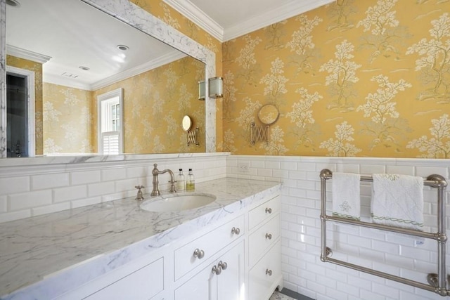 bathroom with vanity, ornamental molding, wallpapered walls, and wainscoting