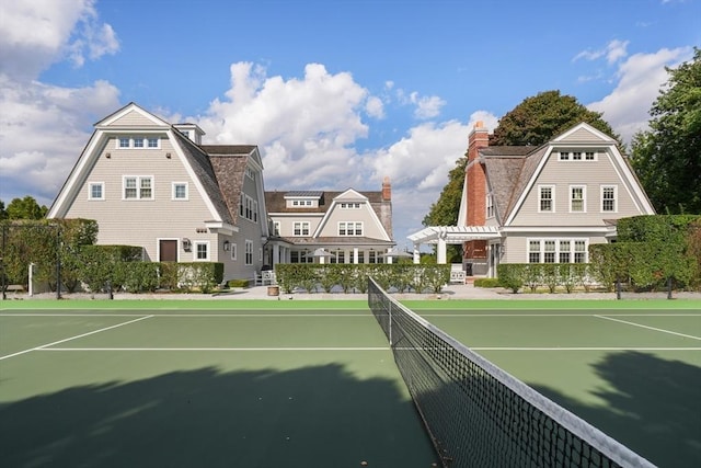 view of tennis court with fence and a pergola