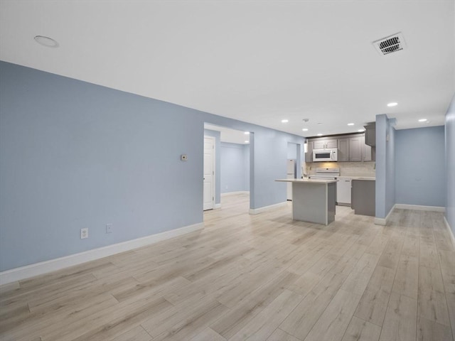 24 Bettys Pond Rd Unit K, Barnstable, MA 02601 - kitchen featuring white microwave, a kitchen island, light wood-style floors, decorative backsplash, and open floor plan