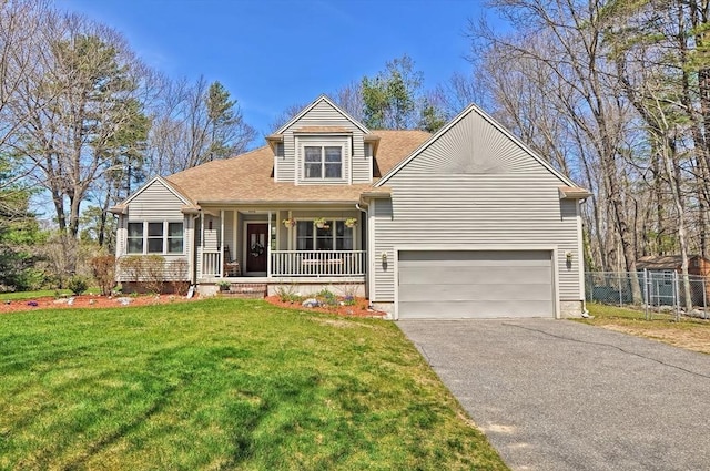 traditional-style home with a porch, driveway, fence, a front lawn, and an attached garage
