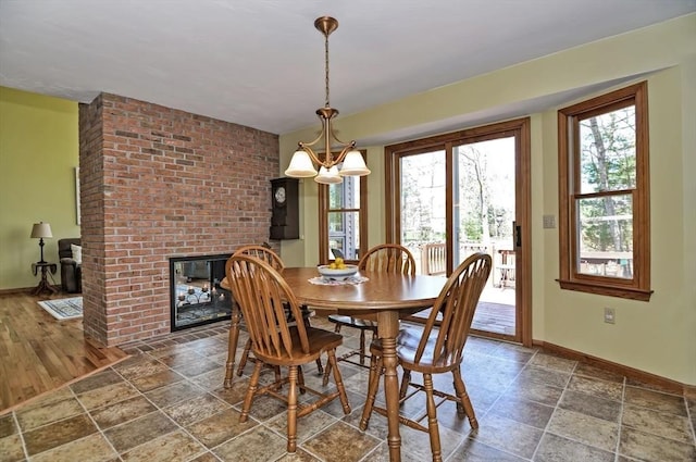 dining room with baseboards, stone finish floor, and a fireplace