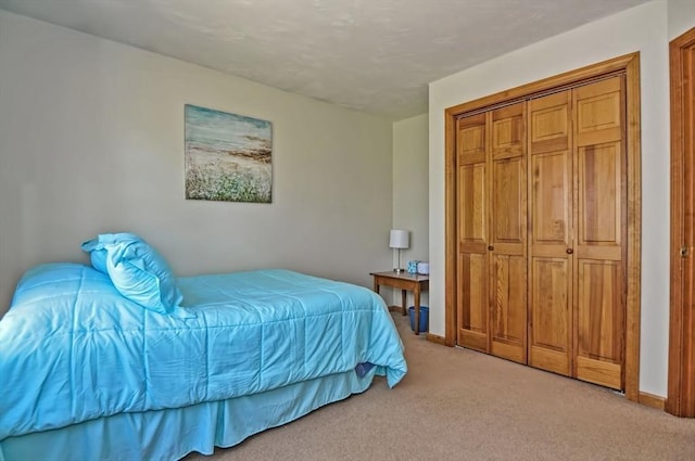 bedroom with baseboards, light colored carpet, and a closet