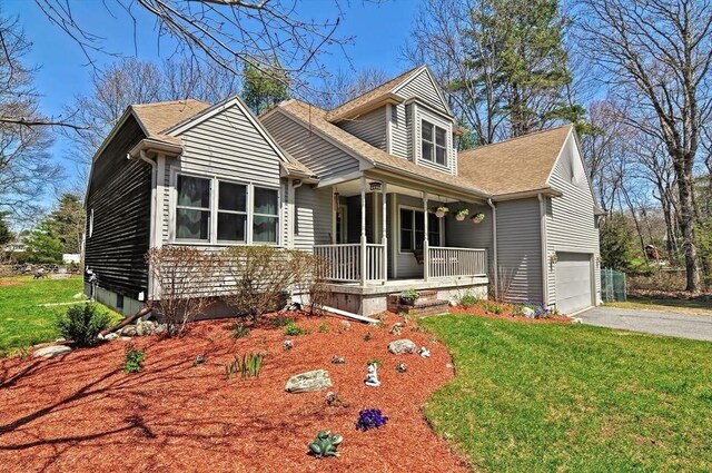 view of front of house featuring covered porch, an attached garage, aphalt driveway, and a front yard