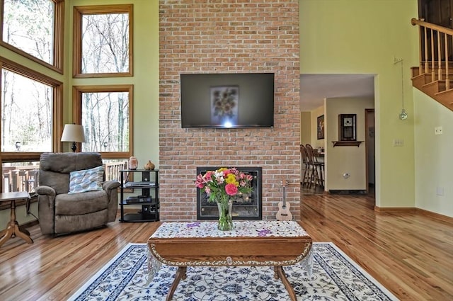 living area with a high ceiling, a fireplace, stairs, and wood finished floors
