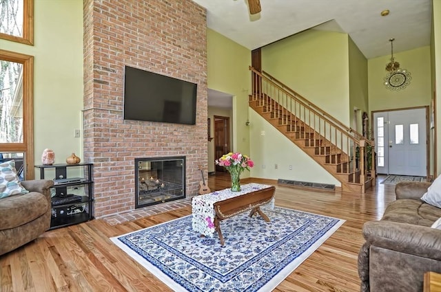 living room featuring stairway, a wealth of natural light, wood finished floors, and a towering ceiling