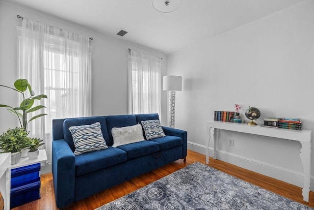 living area with dark wood-type flooring, a healthy amount of sunlight, visible vents, and baseboards