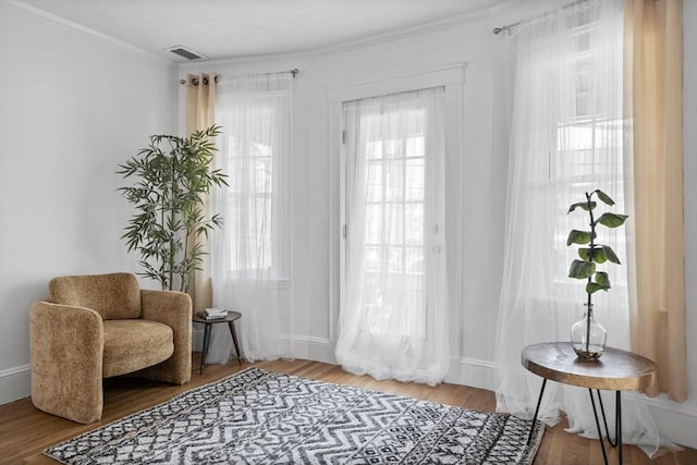 sitting room featuring visible vents, crown molding, baseboards, and wood finished floors