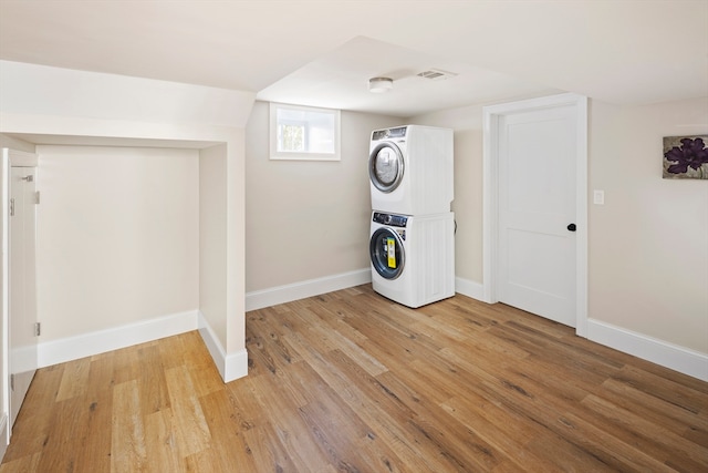 washroom with light wood-type flooring and stacked washer / drying machine