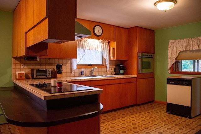 kitchen featuring tile countertops, stainless steel oven, a wealth of natural light, and white dishwasher