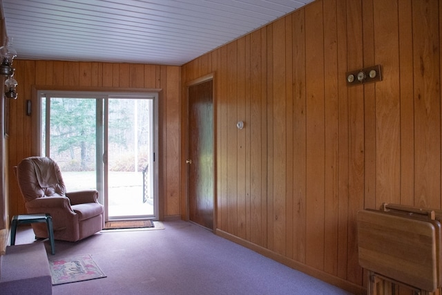 doorway to outside featuring light carpet and wood walls