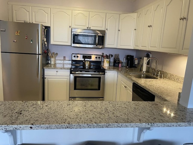 kitchen featuring a sink, stainless steel appliances, light stone countertops, and white cabinets