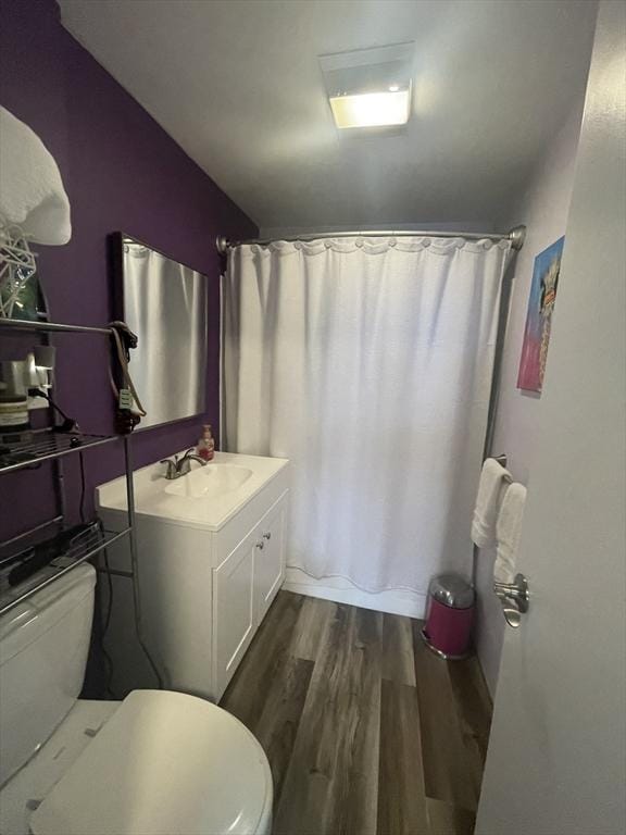 full bathroom featuring vanity, a shower with shower curtain, toilet, and wood finished floors