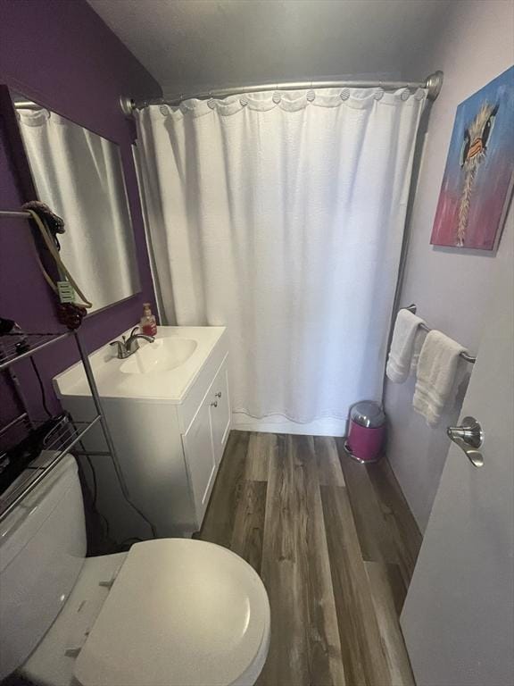 bathroom featuring curtained shower, toilet, vanity, and wood finished floors