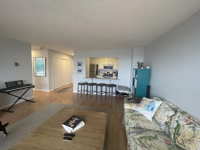 living area with baseboards and wood finished floors