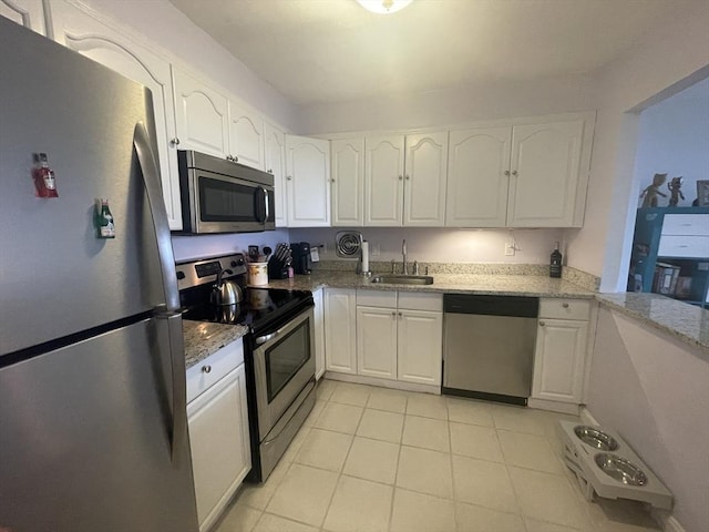 kitchen with white cabinetry, light stone countertops, appliances with stainless steel finishes, and a sink