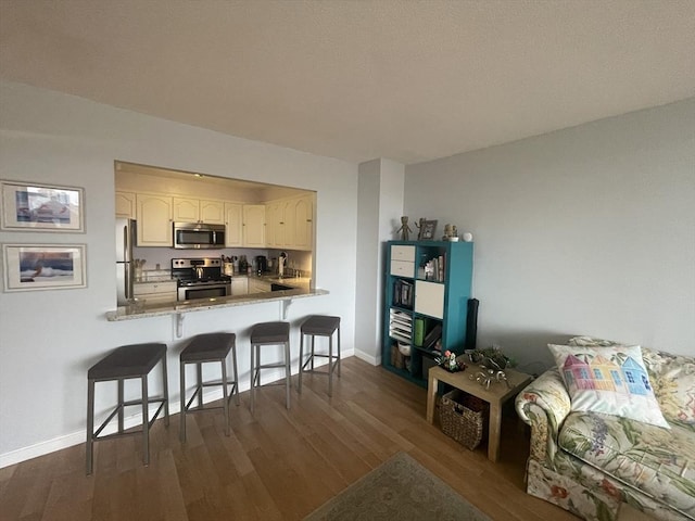 kitchen featuring stainless steel appliances, baseboards, dark wood-type flooring, and a breakfast bar