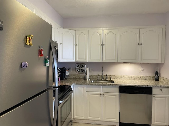 kitchen featuring visible vents, a sink, white cabinetry, stainless steel appliances, and light stone countertops