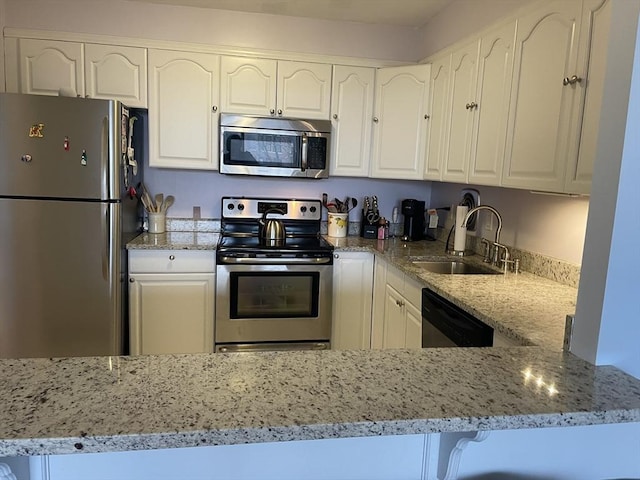 kitchen featuring white cabinetry, light stone counters, appliances with stainless steel finishes, and a sink